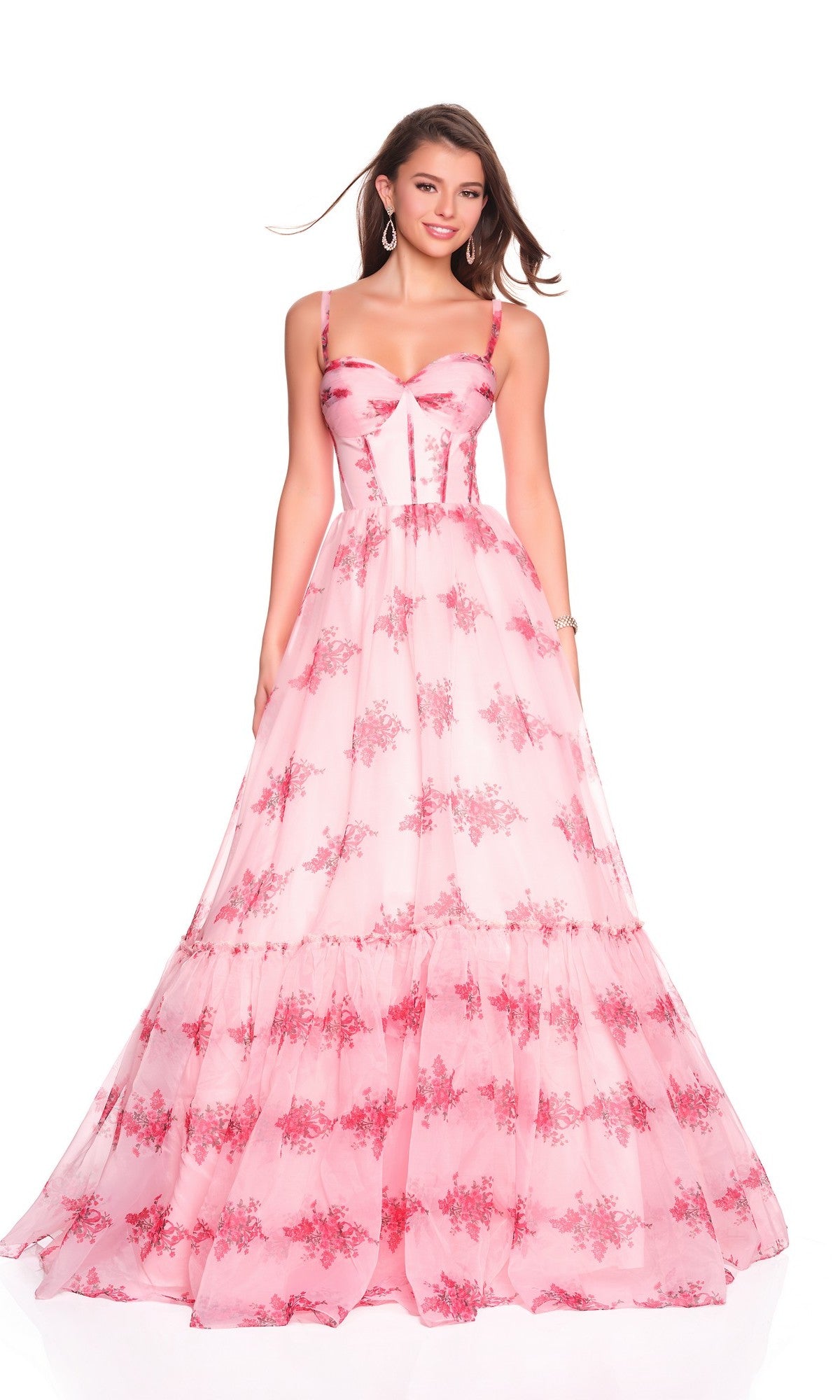A woman wears the Dave and Johnny 12934 long prom dress, featuring a floor-length pink floral design with a sleeveless satin corset bodice and an A-line chiffon skirt, posing against a plain white background.